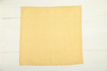 Light yellow napkin on white wooden table, top view