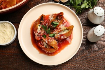 Delicious conchiglie pasta with ricotta cheese, tomato sauce and parsley on wooden table, flat lay