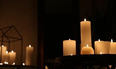Many burning candles on wicker table, closeup. Space for text