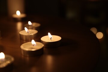 Many burning candles on table, closeup view