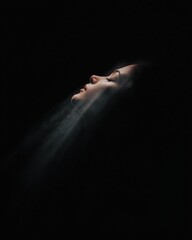 Obraz premium Ethereal portrait of a woman studio dark environment side view serenity and reflection