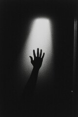 Hand reaching towards light. Silhouette against wall. Hope, escape, or mystery