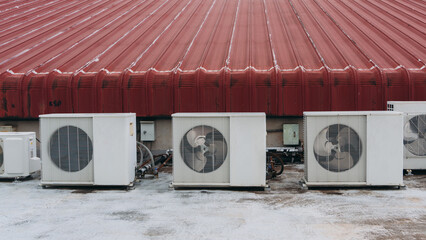 Air conditioner compressor is set up on the roof, along with big cooling units and air vents.