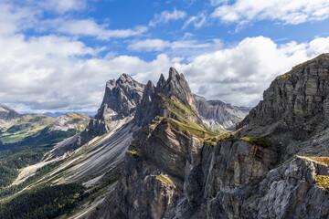 The jagged peaks of Seceda in the Dolomites rise dramatically above steep cliffs and lush alpine meadows, creating a striking and iconic mountain landscape