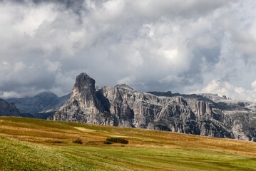 Bright autumn field stretches toward the iconic Sassongher peak in the Dolomites, Italy. Rolling...