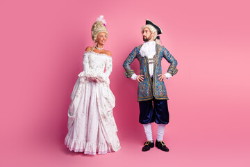 Two people dressed in vintage royal costumes on a pink background at a carnival masquerade event
