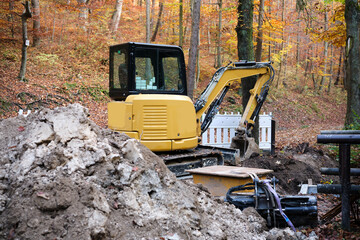 A Compact Loader in a Beautiful Autumn Forest Landscape Perfect for Construction Work © Igor Syrbu