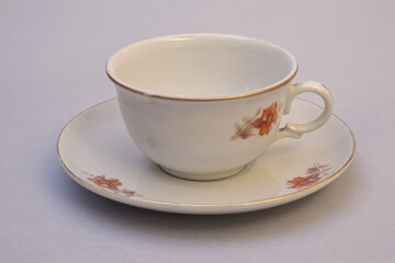 Still life with used vintage porcelain coffee cup and saucer. Close-up on light background with increased depth of field.