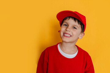 Funny cute boy 6 y.o. in a red cap on a yellow background. Children's room, delivery, dentistry concept.