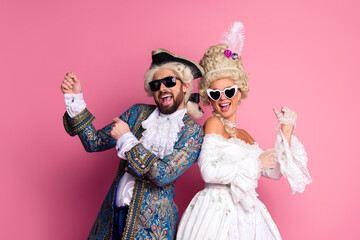 Joyful couple dressed as aristocrats at a carnival event wearing sunglasses and historical costumes...