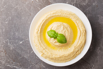 Top view on homemade hummus with olive oil in a white bowl on a dark background. Traditional Arabic snack.