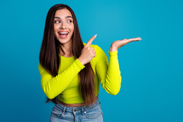Attractive young woman smiling while enthusiastically pointing with her hand in front of a vibrant...