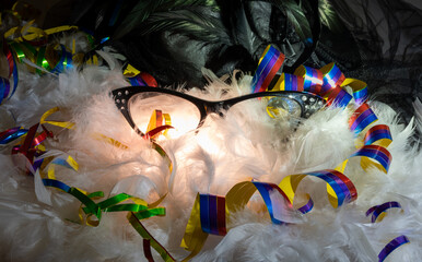 Black carnival glasses with colorful streamers on white feathers