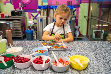 Little girl learning how to cook in a cooking class. Handmade dessert. Making chocolate candy, Child filling heart shaped mold with chocolate