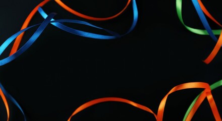 Colorful ribbons in blue, orange, and green on a black background with copyspace
