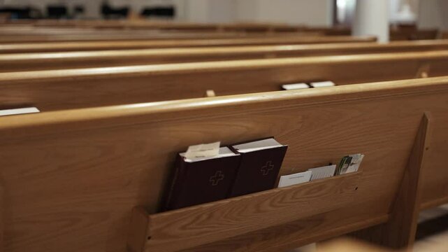 Slow-motion dramatic shot of empty wooden church pews with columns in the background.