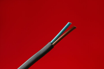 Stripped electrical wire on red background, closeup