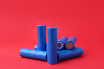 Many AA cell batteries on red background, closeup
