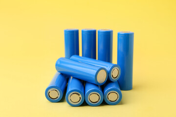 Many AA cell batteries on yellow background, closeup