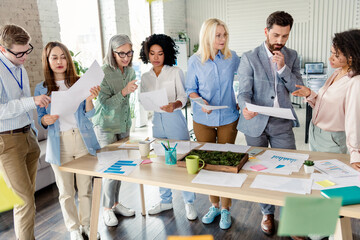 Diverse business team analyzing documents and graphs together in a modern office setting