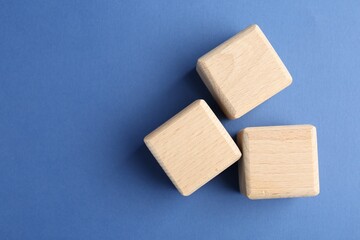 Wooden cubes on blue background, flat lay. Space for text