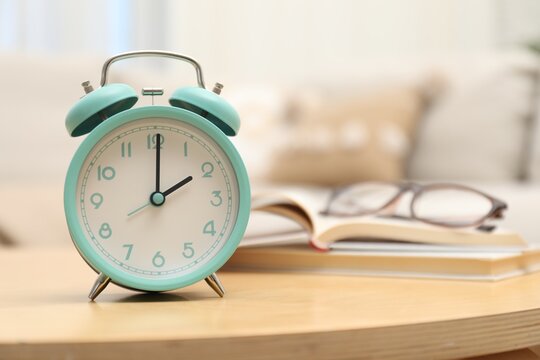 Time for knowledge. Alarm clock, glasses and books on wooden table indoors, closeup
