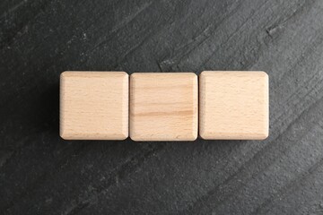 Blank wooden cubes on dark textured table, flat lay