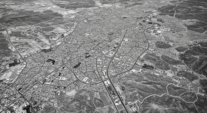 Aerial View of Suburban Cityscape - High-angle black and white aerial photograph of a sprawling suburban city, showcasing its road network and residential areas