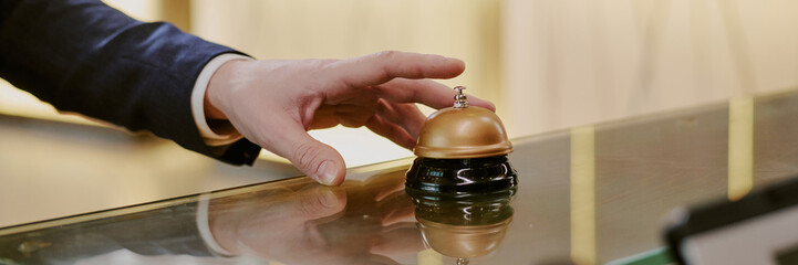 Website banner with unrecognizable male hand ringing reception bell in hotel