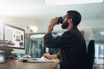 Creative man, computer and drinking with coffee at night for overtime, project deadline or caffeine...