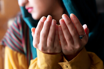 Muslim woman in headscarf and hijab prays with her hands up in air in mosque.Religion praying concept.