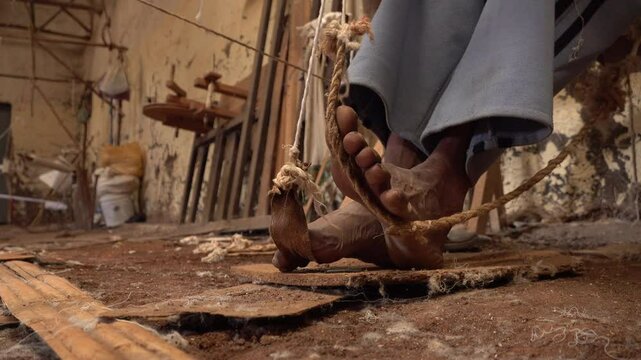 Close-up of bare feet of man using traditional weaving tools in small community factory in Dorze Ethiopia Africa
