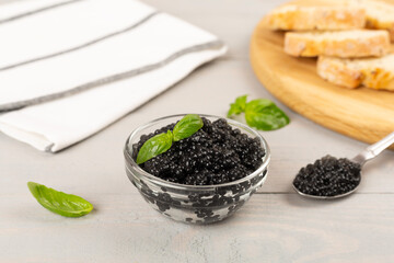 Bowl with black caviar on on wooden table
