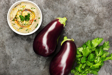 Bowl with baba ganoush, eggplant hummus on black background with ingredients, from above overhead top view, traditional Middle Eastern cuisine concept