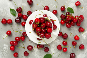 Fresh cherries in bowl on concrete background, top view