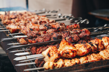 Aromatic shashlik on skewers, browning on the grill. Juicy pieces of meat with a crispy crust, smoke rising upwards, creating an atmosphere of summer recreation in nature