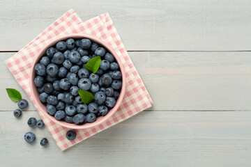 Bowl with fresh bright blueberries on wooden background,top view