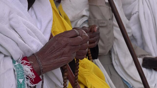 Africa Christian Orthodox religion - close-up senior pilgrim using prayer beads at mass in historic rock-hewn church in Lalibela, Ethiopia
