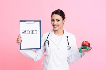 Portrait of smiling female doctor with stethoscope holding diet sign and apple isolated.