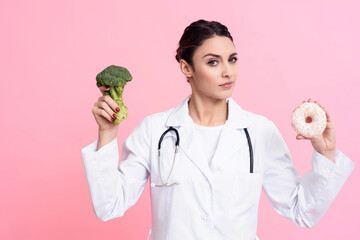 Portrait of doctor with stethoscope holding broccoli and donut isolated.