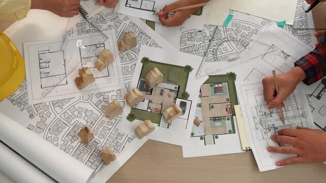 Architect and safety engineer discussion about building construction use blueprint on table with architectural document, measurement tool and wooden block scatter around at modern office. Delineation.