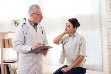 Doctor with stethoscope and female patient in office. Patient's side hurts.