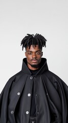 Obraz premium Mysterious black male magician in a dramatic cape captured against a clean white background for a striking visual effect