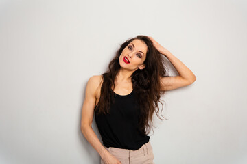 Fototapeta premium Happy beautiful make-up fun woman with red lipstick looking with fun brash grimacing in black summer top on white empty studio copy space background holding long brown hair. Expression fun portrait.
