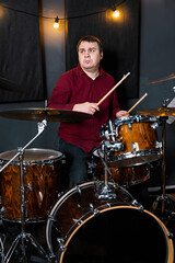 Male Musician Playing Drum Set in Studio with Warm Lighting..