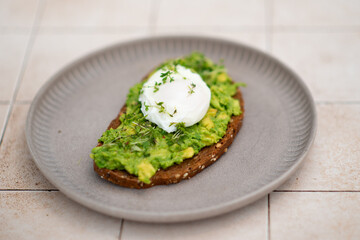 Smashed avocado sandwich with boiled poached egg with flowing yolk.