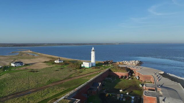 Hurst Point Lighthouse in Milford on Sea, England drone video daytime of classic white lighthouse along southern coast of UK