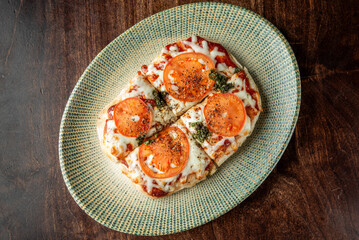 Delicious homemade pizza topped with fresh tomatoes and herbs on a textured plate, showcasing a golden crust and melted cheese. Perfect for food lovers.