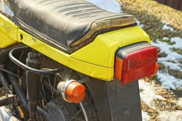 back of leather black torn dirty soft saddle with red plastic warning rear brake light with round...
