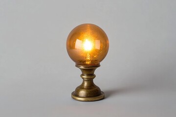 A glowing amber glass orb table lamp with a brass base, emitting a warm light.